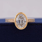 Top front view of 3 CT oval cut lab grown diamond set in beaded milgrain yellow gold bezel.