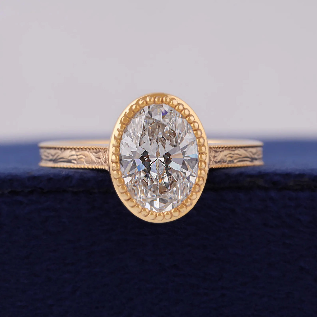 Top front view of 3 CT oval cut lab grown diamond set in beaded milgrain yellow gold bezel.