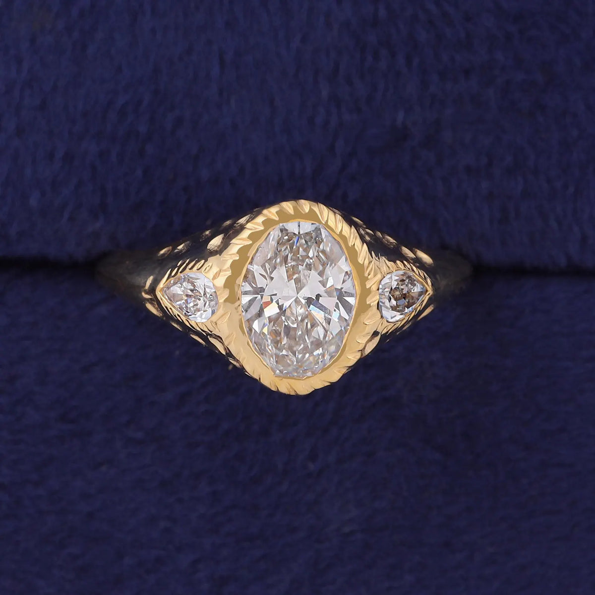 Top view of 3 CT oval lab grown diamond 3-stone signet ring with pear accents in yellow gold.