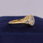 Side profile of wide 14K yellow gold signet ring featuring hammered texture and flush-set pear side diamond