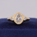 Front view of 3 carat oval lab diamond ring with star-carved bezel edge and twin pear side stones.