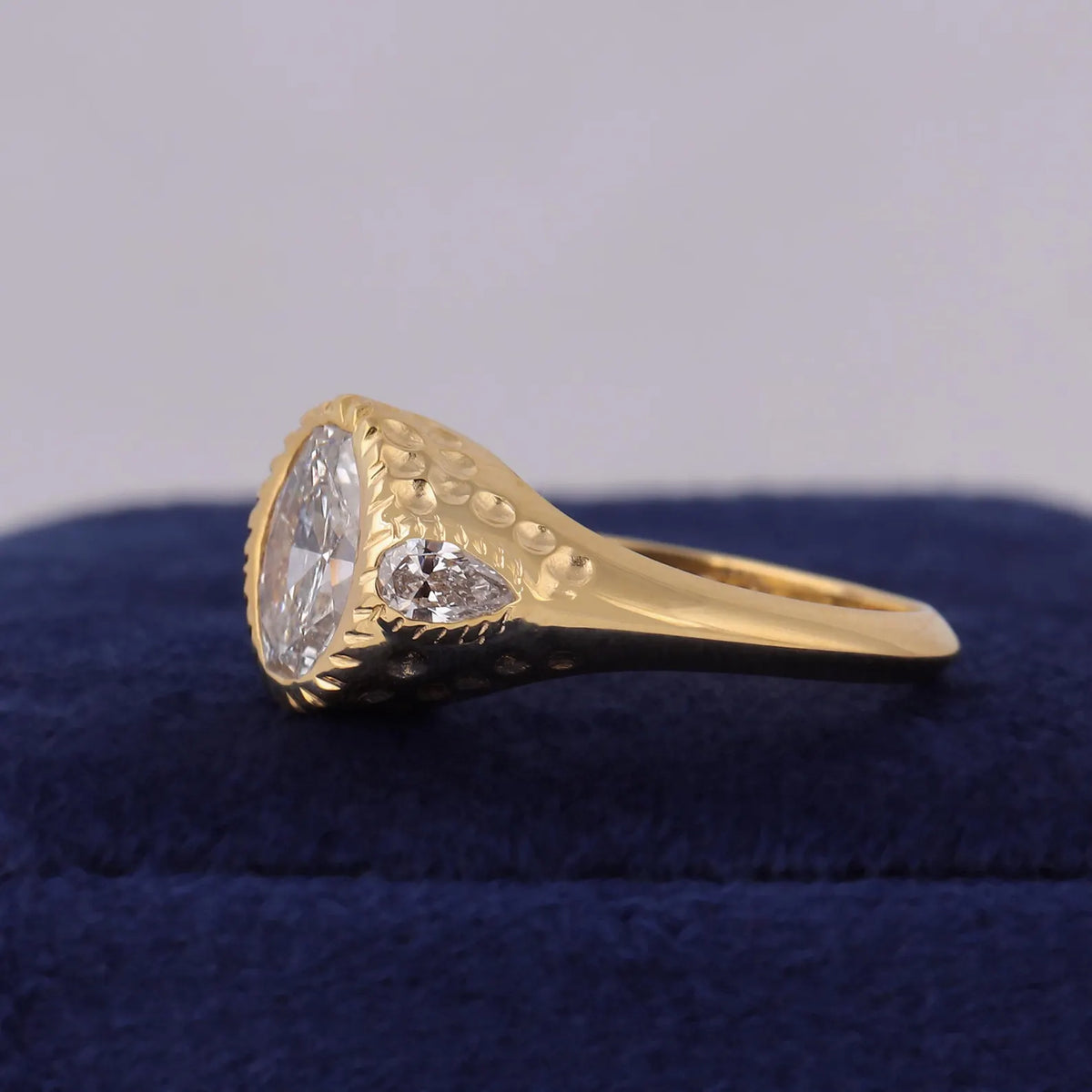 Angled side profile showing chiseled bezel rim and textured band of 3 CT oval lab diamond ring.