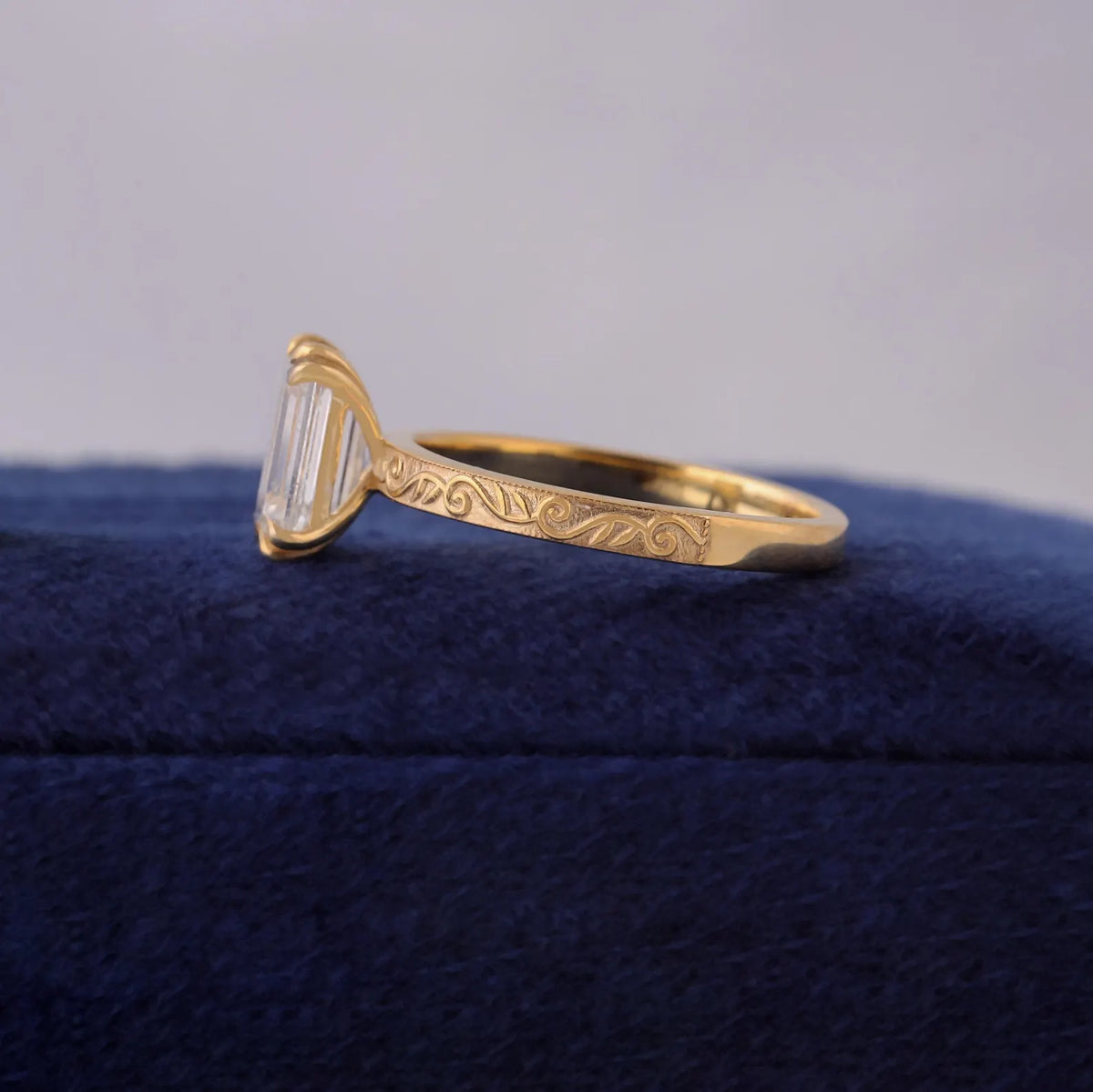 Side view of a 3 CT emerald cut lab grown diamond ring in 14K yellow gold with vintage scroll engraving.