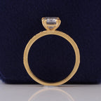 Studio profile view of 3 carat emerald cut lab diamond elevated basket setting in 14K yellow gold.