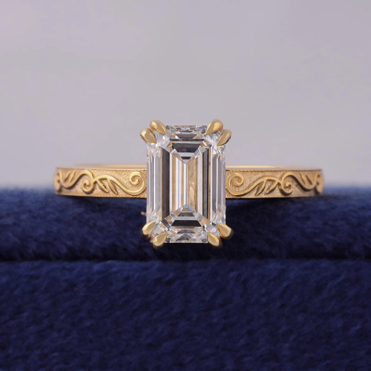 Top front view of 3 CT emerald cut lab grown diamond set on a hand-engraved yellow gold band.