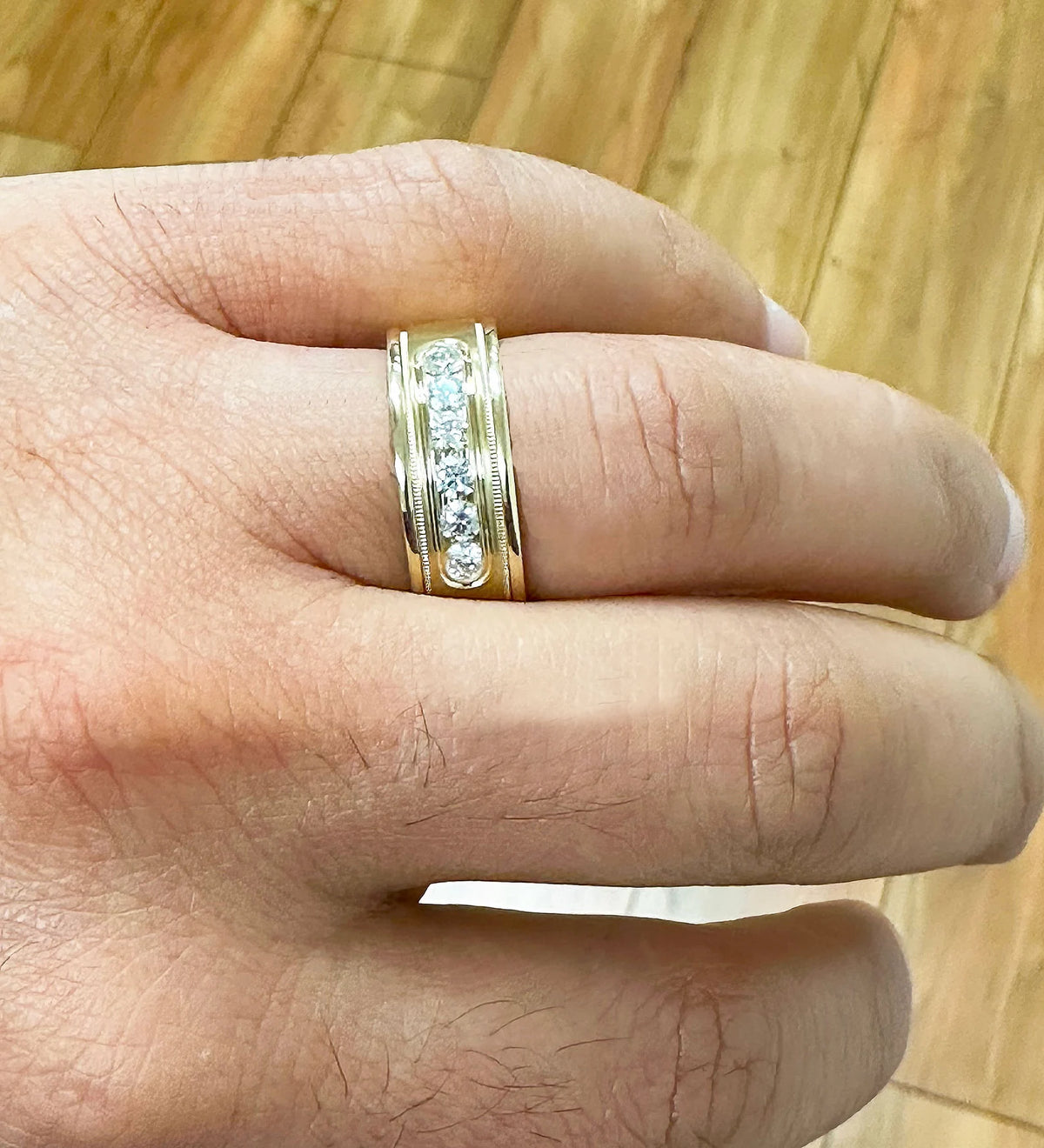Top-down close-up view of the round cut lab-grown diamond band worn on a hand under warm lighting.