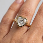Close-up on-hand view showing the sleek yellow gold bezel border framing a 3ct heart diamond.