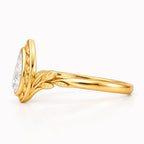 Side profile of yellow gold botanical pear diamond engagement ring showing carved leaf band.