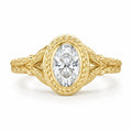 Direct top-down view of a 3 carat oval lab created diamond framed in a laurel leaf engraved yellow gold bezel.