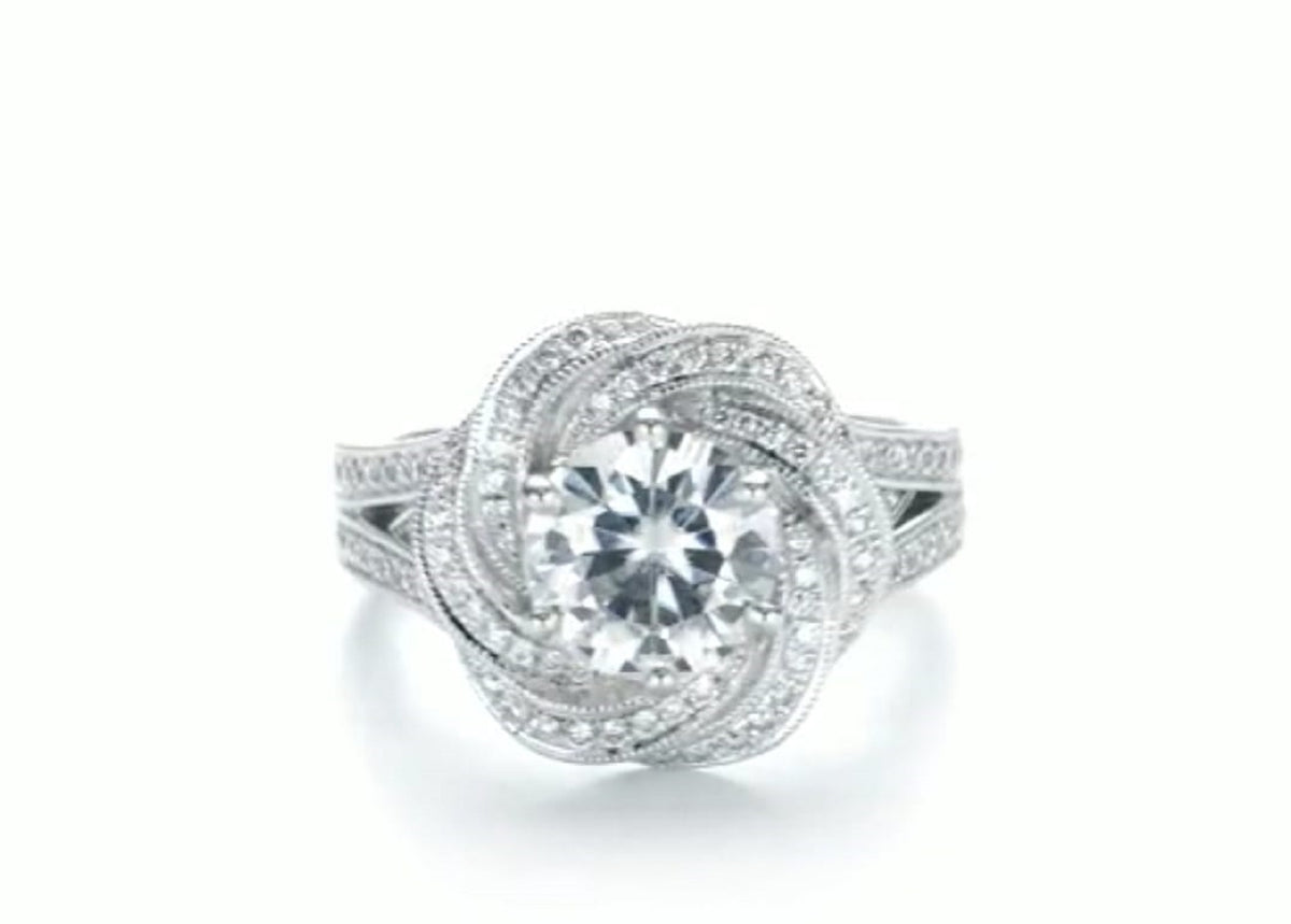 Top-down view of a 2 carat round lab diamond center stone enclosed in a micro-pavé swirl halo setting.