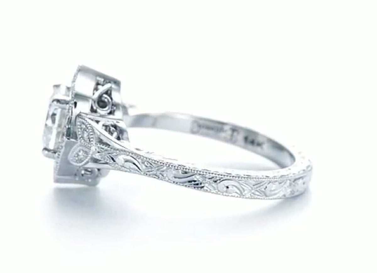 Side view of white gold engagement ring displaying leaf motif shoulder, carved band, and 14K quality stamp inside.