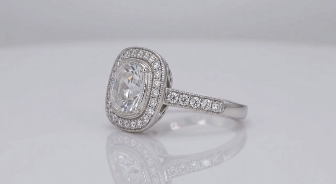 Perspective view highlighting the sparkling cushion cut lab diamond center, beaded milgrain halo, and paved diamond shoulders.