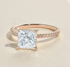 Three-quarter view of a 2 carat princess cut lab grown diamond ring with a thin rose gold pavé band.