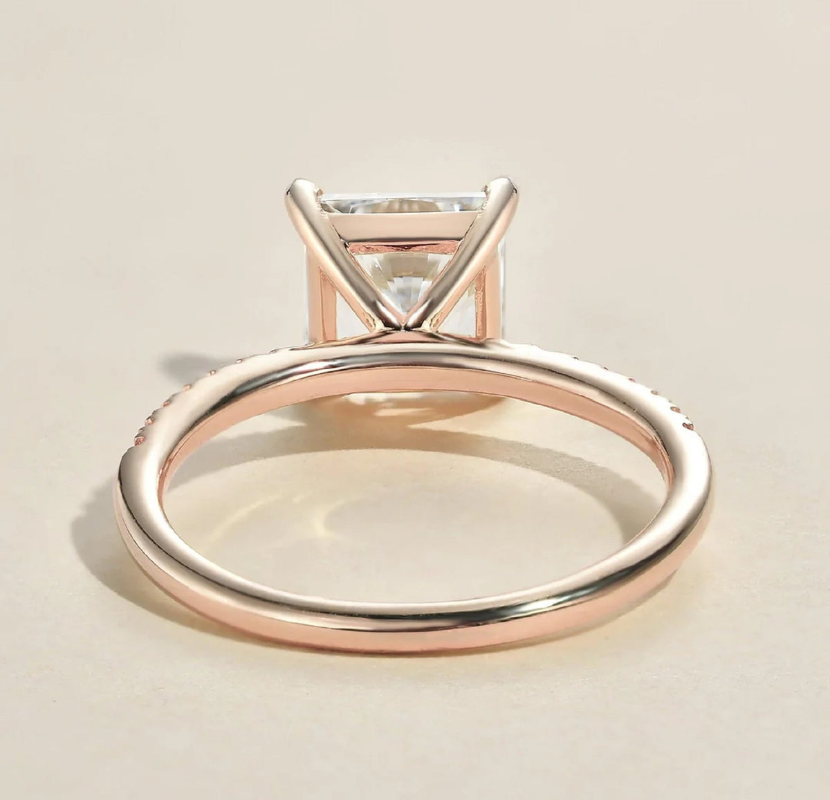 Side profile view showing the slender open basket wire setting and smooth rose gold shank of a 2ct princess cut ring.
