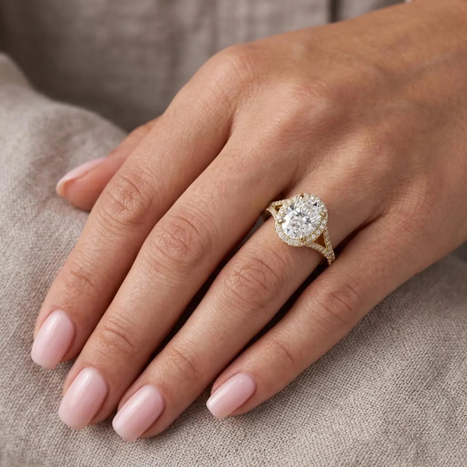 Model wearing a 3 carat oval lab grown diamond halo split-shank ring in yellow gold.