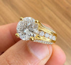 Close-up of a 3 ct round brilliant lab diamond ring showing channel set side stones and pavé prongs in yellow gold.