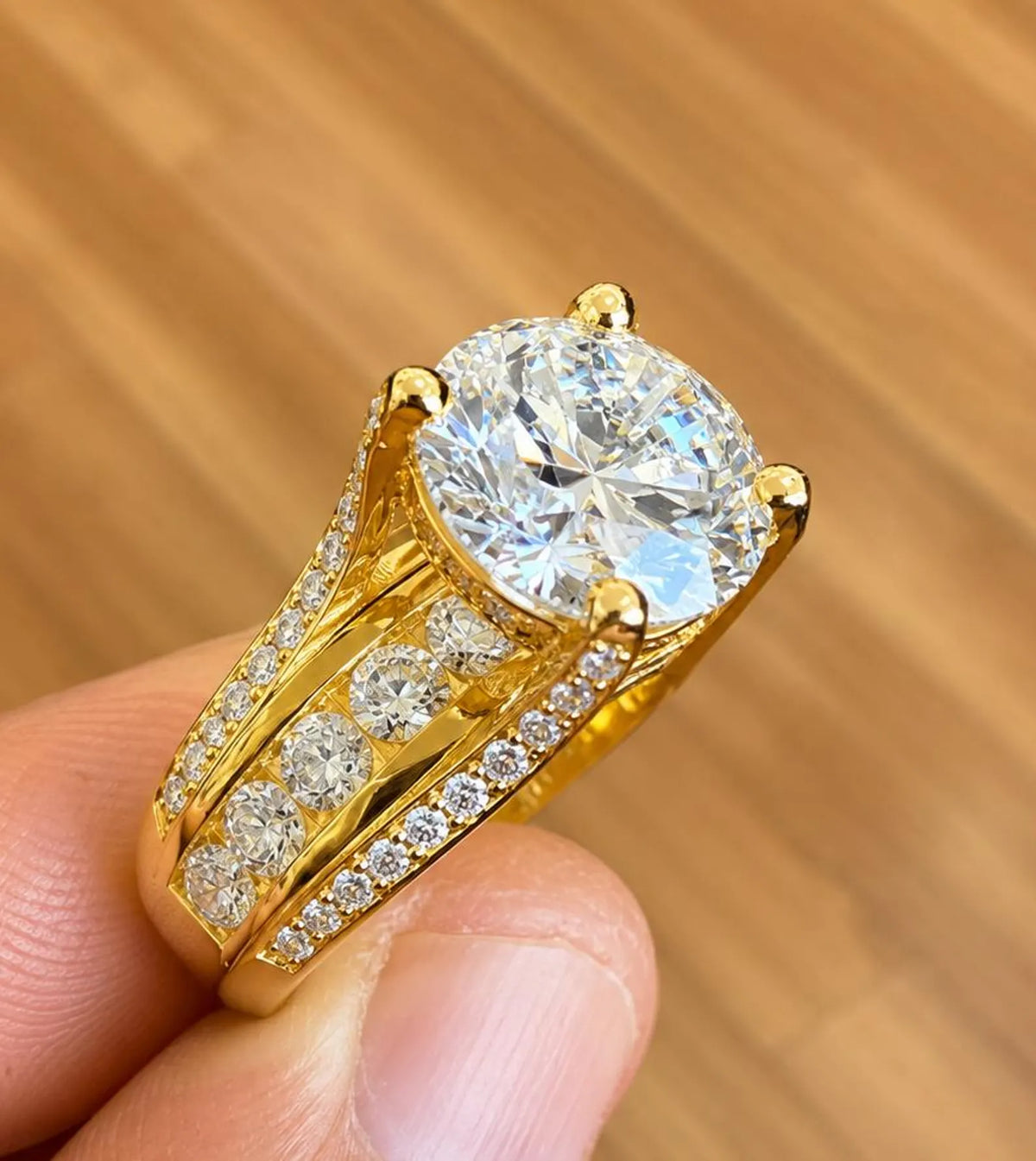 Close-up view of the channel-set round accent diamonds running along the wide yellow gold band.
