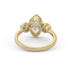 Angled view of a 3 carat marquise lab-grown diamond bezel ring flanked by round bezel side stones in 14K yellow gold.