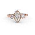 Direct top view of a 3 carat marquise cut lab diamond three-stone bezel engagement ring set in 14K rose gold.