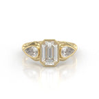Front view of a 3 carat emerald cut lab grown diamond ring with bezel-set pear side stones in 14k yellow gold.