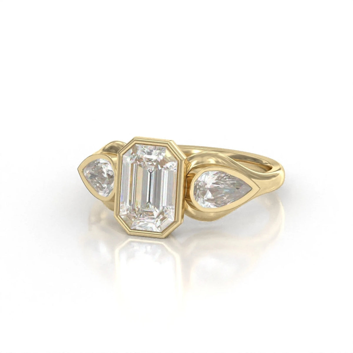 Angled top view showing the emerald cut center and pear side diamonds in a yellow gold bezel setting.