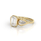 Three-quarter side perspective of a 3 carat emerald cut bezel engagement ring in yellow gold.