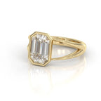 A yellow gold ring featuring a large, bezel-set emerald-cut diamond. The diamond is clear and does not contribute to the color mapping according to the schema rules, so the product color is determined solely by the gold metal setting and band.