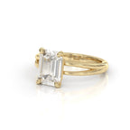 Perspective view of a 3 carat emerald cut lab grown diamond solitaire ring in yellow gold with a split shank band.