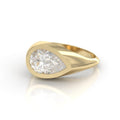 High-angle view of a 3 CT pear cut lab grown diamond signet ring set in a chunky 14K yellow gold flush bezel.