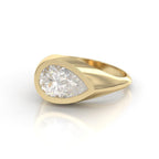 High-angle view of a 3 CT pear cut lab grown diamond signet ring set in a chunky 14K yellow gold flush bezel.