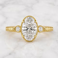 Top-down view of 2 Carat Oval Cut Lab Grown Diamond Engagement Ring showing milgrain trim, side accents, and chevron engraved band