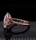 Close-up side perspective of a 4 CT marquise lab created diamond ring with sculpted leaf filigree shank in rose gold.