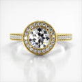 Top-down view of a 3 CT round cut lab grown diamond engagement ring in yellow gold with round milgrain halo and pave band.