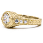 Close-up angle of yellow gold lab grown diamond engagement ring showing side diamond accents and engraved band