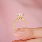 Side profile of 2 CT Asscher cut lab grown diamond ring in yellow gold held between fingers showing floral engraved basket gallery
