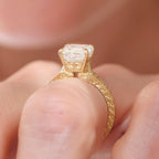 A close-up shot of a yellow gold ring with a large clear rectangular gemstone, worn on a finger.