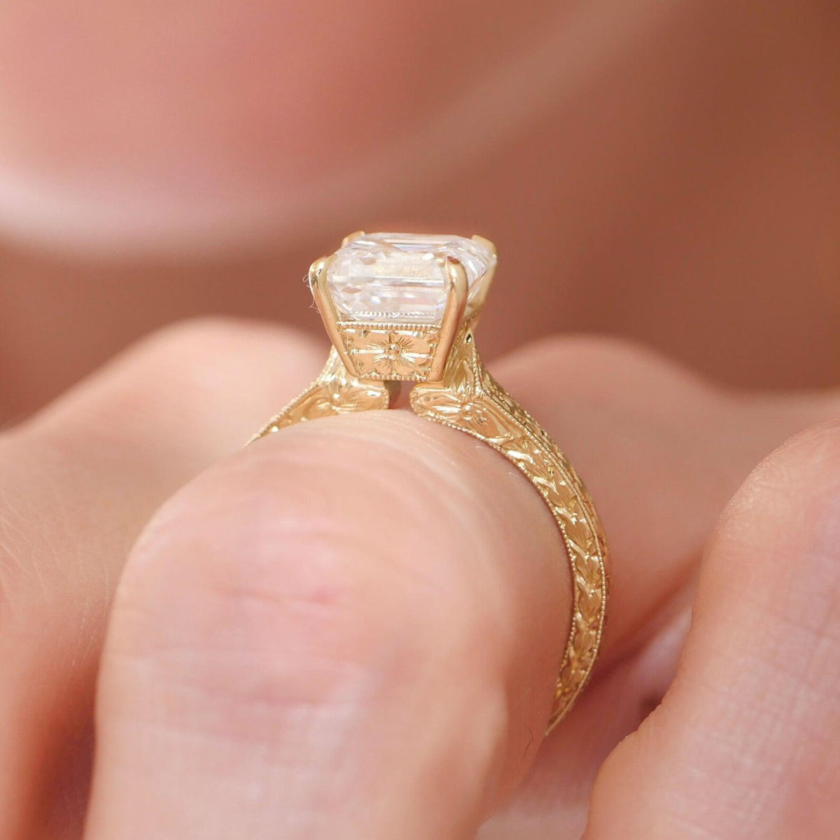 A close-up shot of a yellow gold ring with a large clear rectangular gemstone, worn on a finger.