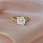 Macro side profile view of yellow gold Asscher diamond ring displaying carved flower gallery and textured shank