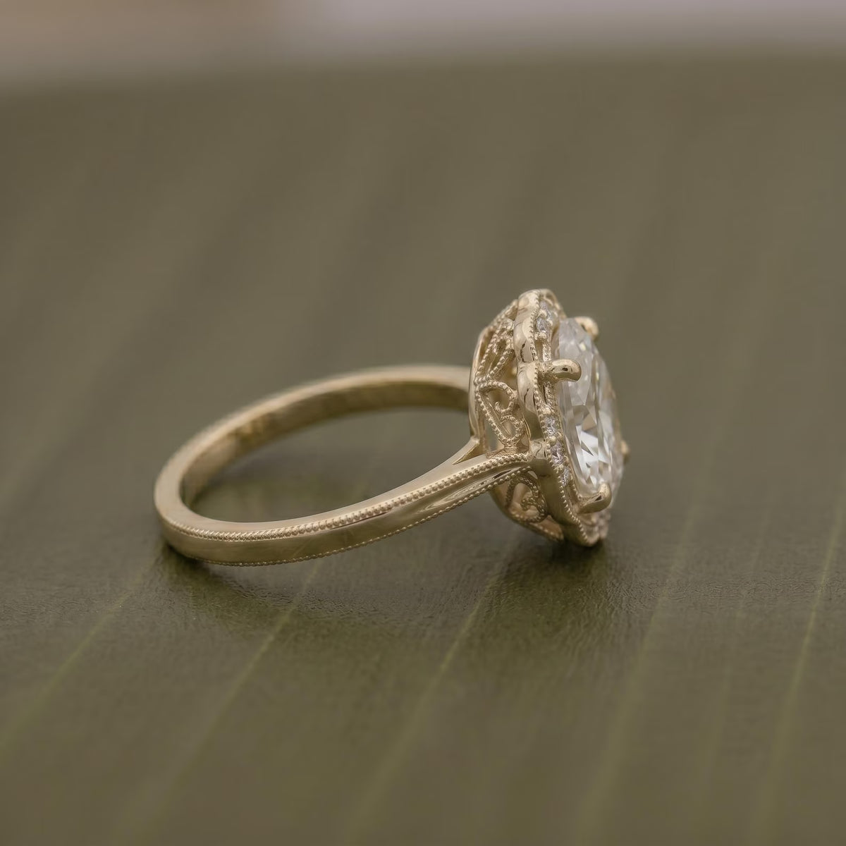 Side profile view of a 3 CT oval cut lab grown diamond engagement ring in yellow gold showing intricate filigree basket detail.