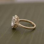 Close-up side perspective of a yellow gold vintage engagement ring featuring a 3 CT oval center diamond and decorative openwork gallery.