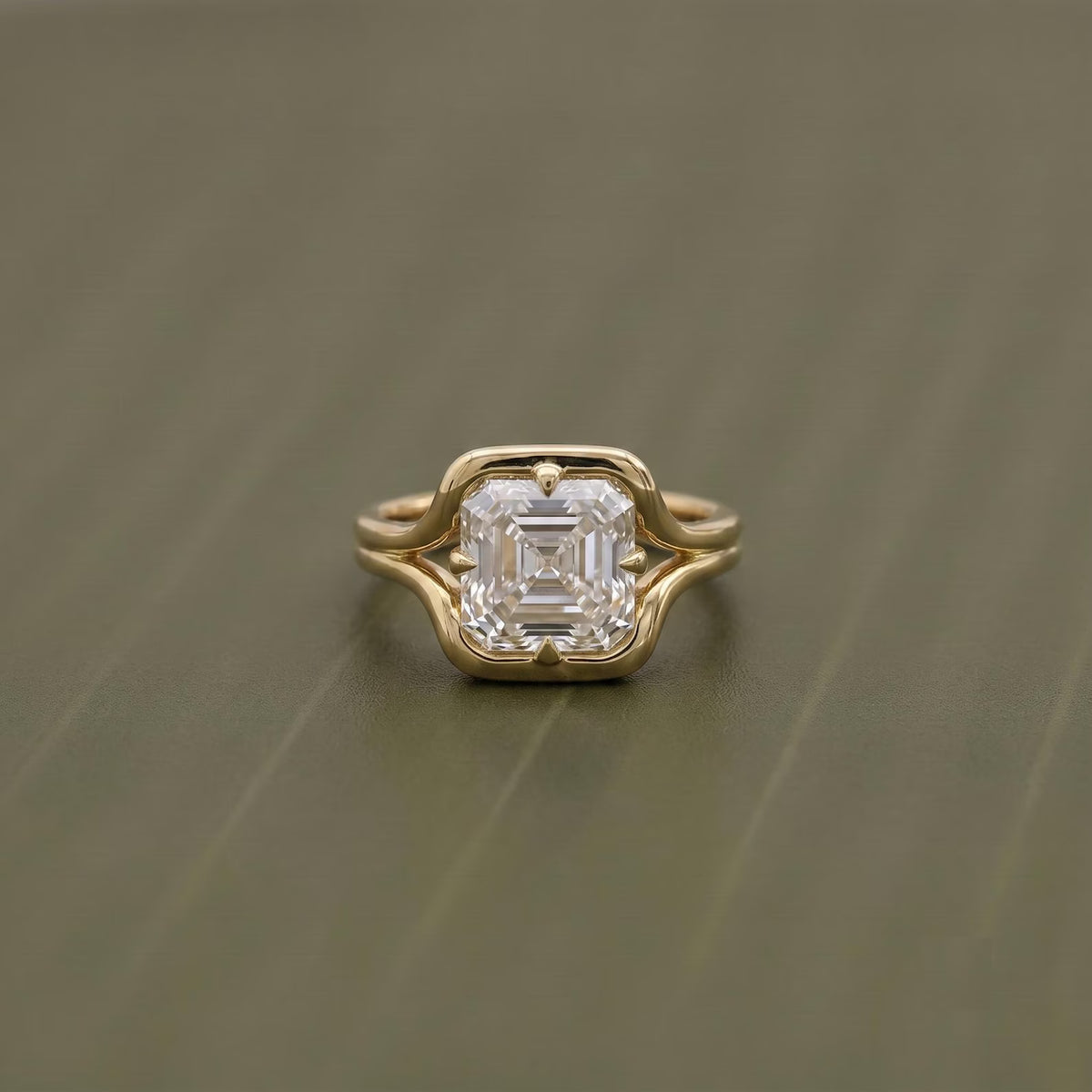 Top-down view highlighting the step-cut facets of a 2 CT Asscher lab diamond in a yellow gold frame.