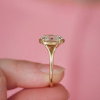 Close-up side profile shot of a 3 carat oval lab diamond ring held against a pink backdrop showing the open undergallery work.