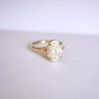 Three-quarter perspective angle view of a 3ct oval lab grown diamond solitaire ring with split cathedral shoulders resting on a smooth white surface.