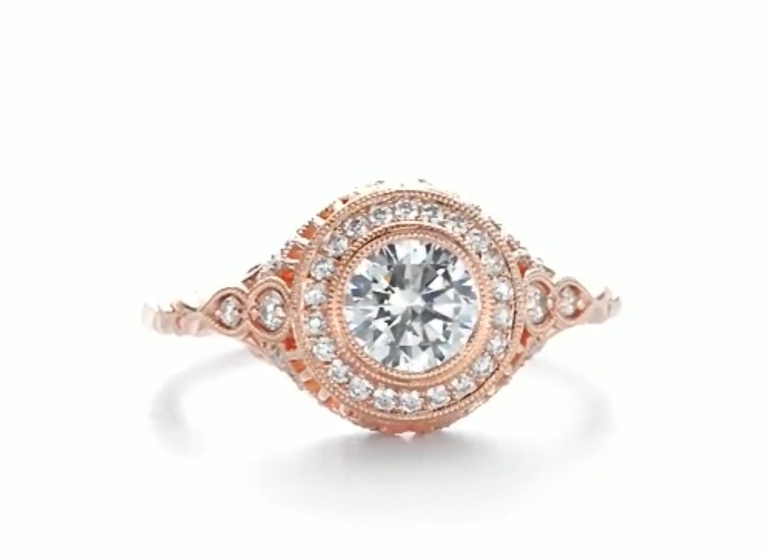 Top-down view of a 3 CT round cut lab grown diamond engagement ring in rose gold with a milgrain halo and engraved band.