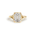 Front top-down studio view of a 3 carat emerald cut lab grown diamond ring in yellow gold featuring milgrain bezel frame.
