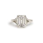 Front studio macro view of a 3 carat emerald cut lab diamond solitaire ring set in white gold or platinum with a milgrain bezel.