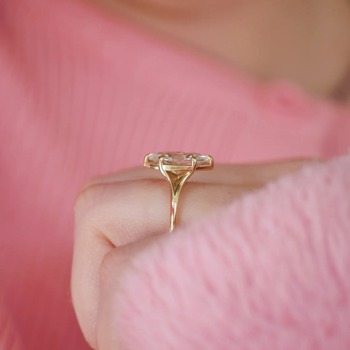 Perspective side view of a 3 carat marquise lab diamond engagement ring with split cathedral shoulders worn on a hand.