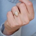 Direct on-finger view of a 3 carat marquise lab grown diamond ring with split shoulders showcased with a blue sweater backdrop.