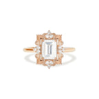 Studio top-down view of a 3 carat emerald cut lab grown diamond engagement ring crafted in 14k rose gold with an ornate Art Deco filigree halo frame.