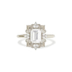 Front studio shot of a 3 carat emerald cut lab diamond ring set in white gold or platinum with an antique sunburst halo frame.